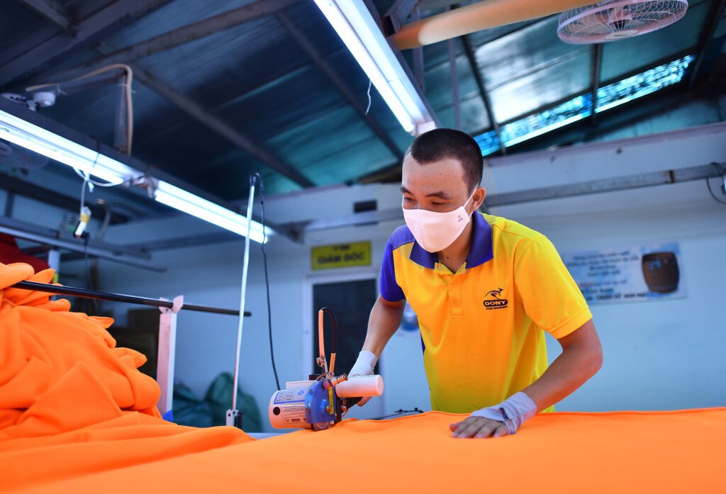 Doanh nhân 8X Phạm Quang Anh cũng đích thân lao vào công việc cắt vải cùng công nhân - Ảnh: Quốc Hải