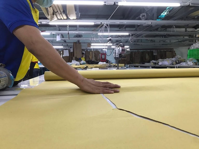  Người thợ lành nghề đang từng bước trải vải để thực hiện công đoạn cắt